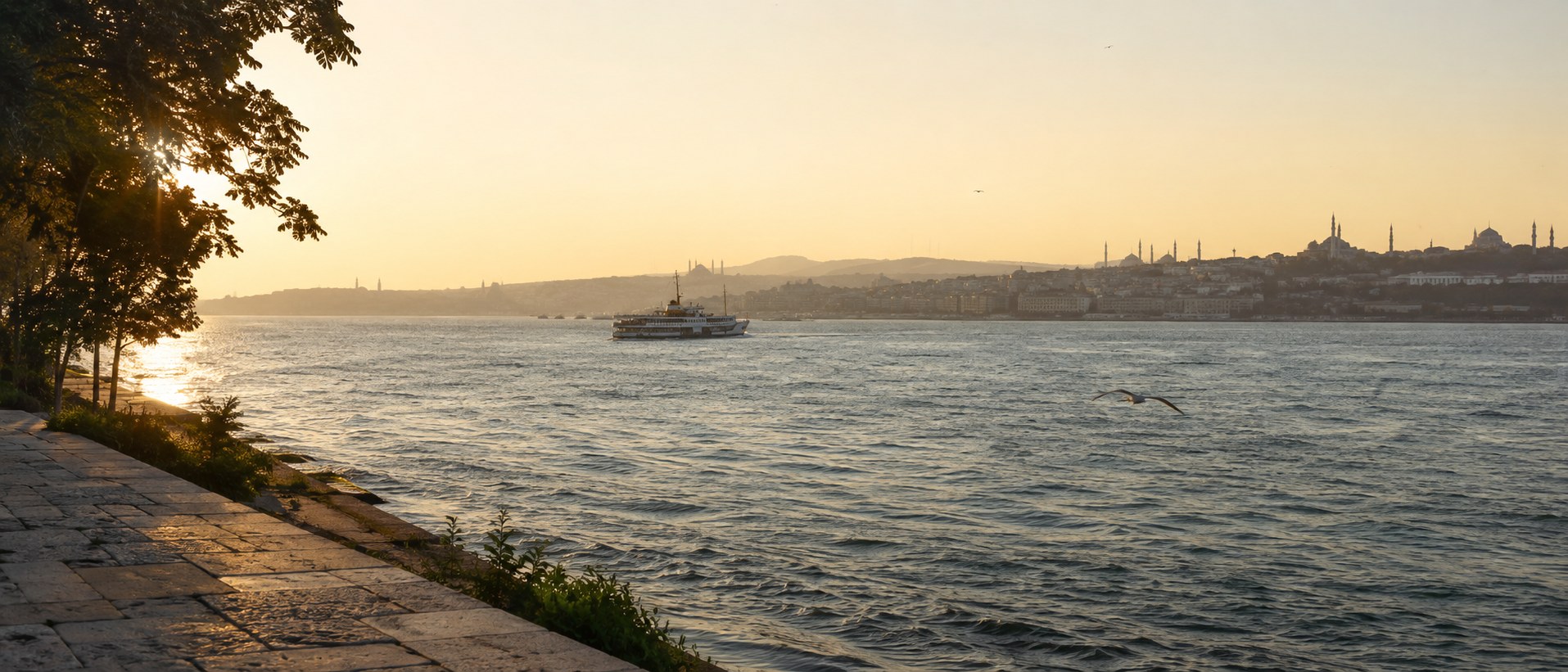 Early sunlight across the Bosphorus from Istanbul's Asian shore, with a commuter ferry and the historic skyline beyond